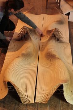 a woman is working on a piece of wood that has been carved into the shape of an umbrella