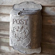 a metal post box mounted to the side of a wooden wall