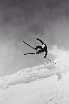 a man flying through the air while riding skis on top of a snow covered slope