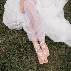 a woman in white dress and barefoot sandals sitting on the grass with her feet up