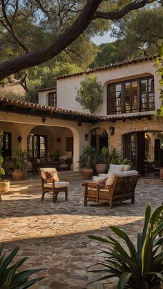 an outdoor patio with chairs and potted plants in front of a large stone building