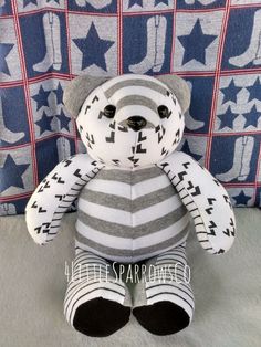 a teddy bear sitting on top of a bed next to a blue and white wall