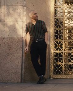 a man standing in front of a building with his hand on his hip and looking off to the side