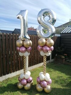 two large balloons with the number twenty eight hanging from them in front of a fence