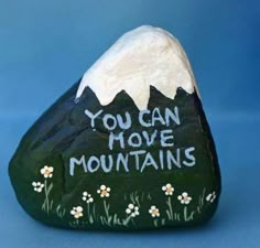 a painted rock with the words you can move mountains on it and daisies below