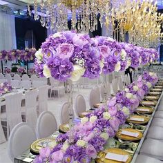 a long table with purple flowers and place settings on it for an elegant dinner party