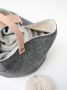 a gray bag sitting on top of a white table next to a ball of yarn