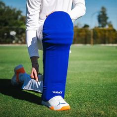 a soccer player with his foot on the back of a blue legcover while standing on a green field