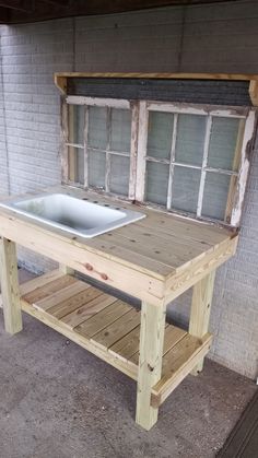 a wooden table with a white sink on it's top in front of a brick wall