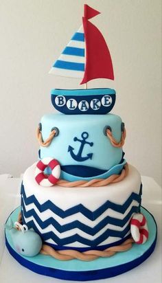 a blue and white cake with a red sailboat on top, sitting on a table