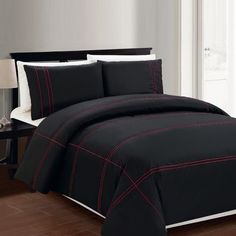 black and red comforter set with white trimmings on wooden floor next to window