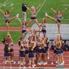 a group of cheerleaders standing on top of a track with their hands in the air