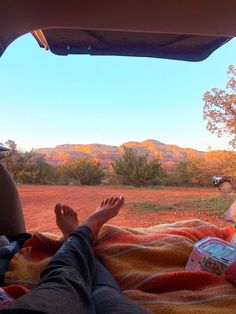 a person laying on top of a blanket in the back of a truck with their feet up