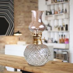 a clear glass bottle sitting on top of a wooden table next to a brick wall