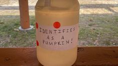 a plastic bottle with writing on it sitting on top of a wooden table next to a tree