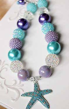 "This necklace features a beautiful rhinestone starfish pendant. Part of my \"Summer Nautical\" line, with a summery palette of aqua blue, purple and iridescent sparkle inspired by a mermaid at sea, it is the perfect accent for your photo shoot or outfit. To see more summer themed necklaces visit my summer section: https://www.etsy.com/shop/ChunkyStuffByLBB?section_id=17113232&ref=shopsection_leftnav_4 ✔ Necklaces come in child to adult sizes with a 2\" extender chain and jumbo lobster clasp Blue Beaded Necklace For Birthday, Blue Jewelry With Colorful Beads For Birthday, Blue Beaded Necklace For Birthday With Round Beads, Blue Necklaces With Starfish Charm And Round Beads, Blue Round Bead Necklaces For Birthdays, Blue Round Beads Necklaces For Birthday, Summer Necklaces, Pen Ideas, Purple Beads