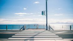 an empty street next to the ocean with a traffic light on it's side