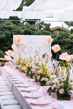 the table is set up with pink and white plates, napkins, and flowers