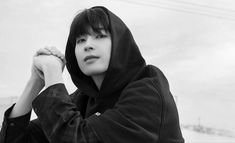 a woman in a hoodie is posing for a black and white photo with her hands on her head