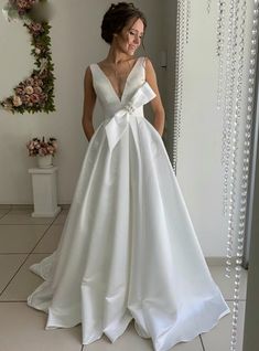 a woman standing in front of a mirror wearing a white wedding dress with deep v - neck