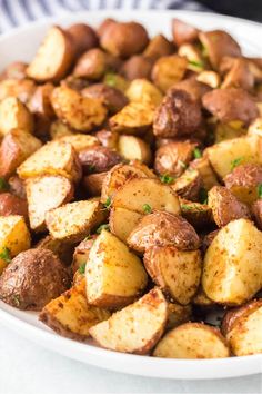 a white bowl filled with cooked potatoes on top of a table next to a blue and white striped napkin