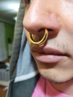 a close up of a person with a ring on his nose and wearing a pink shirt