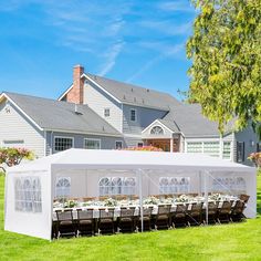 a large white tent set up in front of a house with many tables and chairs