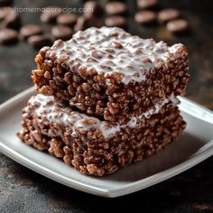 two pieces of chocolate rice krispy treats on a plate with coffee beans in the background