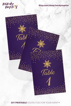 three purple and gold table numbers with sun on them