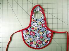 an apron made out of fabric with flowers on it and a red handled scissors next to it