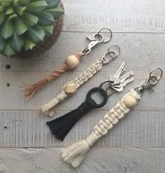 four keychains with tassels on them sitting next to a potted plant