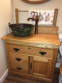 an old fashioned sink sits on top of a wooden cabinet