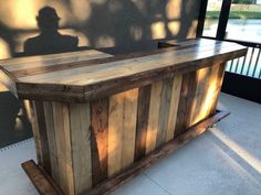 a wooden bar sitting on top of a sidewalk next to a building with a shadow cast on the wall