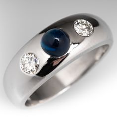 This fabulous vintage ring is centered with a flush set, round sapphire cabochon with a high dome, weighing 1.10 carats. The sapphire is flanked on either side by a flush set, round transitional brilliant cut diamond. The ring measures 7.6mm at the top, rises 6.5mm above the finger, tapering to 4.2mm wide and 1.4mm thick at the base of the shank. It is currently a size 8.5. The ring has light porosity. Luxury Sapphire Cabochon Ring For Anniversary, Luxury Domed Cabochons For Formal Occasions, Classic Cabochon Sapphire Ring For Formal Occasions, Formal Polished Finish Oval Cabochon Sapphire Ring, Formal Domed Cabochon Sapphire Ring, Classic Formal Cabochon Sapphire Ring, Classic Formal Sapphire Cabochon Ring, Formal Fine Jewelry Domed Cabochons, Formal Domed Cabochons Fine Jewelry