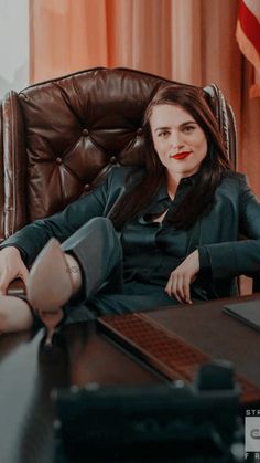 a woman sitting in an office chair with her feet up on the desk next to a laptop