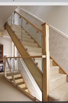 a stair case with glass railing and wooden handrails in a living room next to a bookshelf