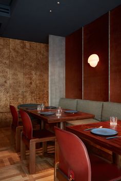 an empty restaurant with wooden tables and red chairs in front of wood paneled walls