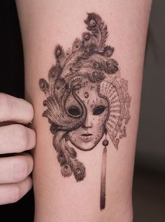 a woman's arm with a tattoo on it that has a mask and feathers