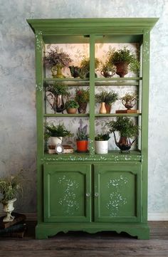 a green china cabinet with potted plants on top