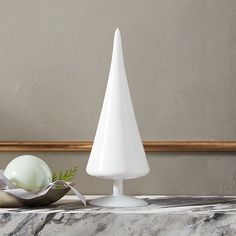 a white vase sitting on top of a marble counter next to a bowl and an egg