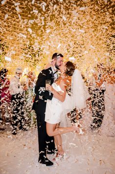 a newly married couple kissing under confetti