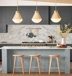 three stools sit in front of an island with marble countertops and gray cabinets