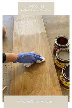 a person in blue gloves is wiping down some paint on a wooden table with the words, the secret to my customized wood stain