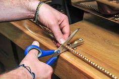 a person cutting something with a pair of scissors on top of a wooden countertop