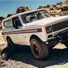 a white truck parked on top of a rocky hill next to a rock filled hillside