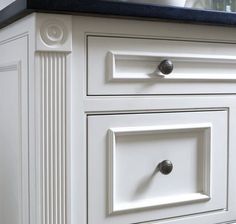 a white cabinet with black counter top and knobs on it's sides, in a kitchen