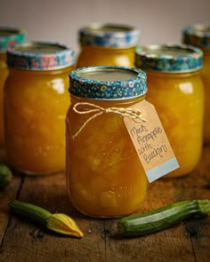 jars filled with pickles sitting on top of a wooden table