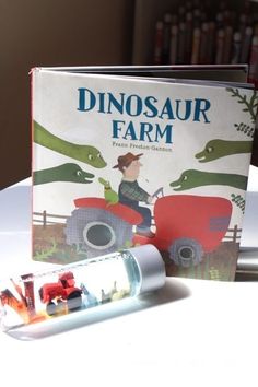 a children's book about dinosaurs and farm animals on a table next to an empty pill bottle