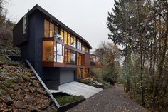 a modern house in the woods with stairs leading up to it's upper level