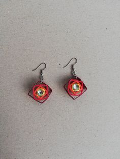 the earrings are made out of red paper and silver beads, with an origami design on them